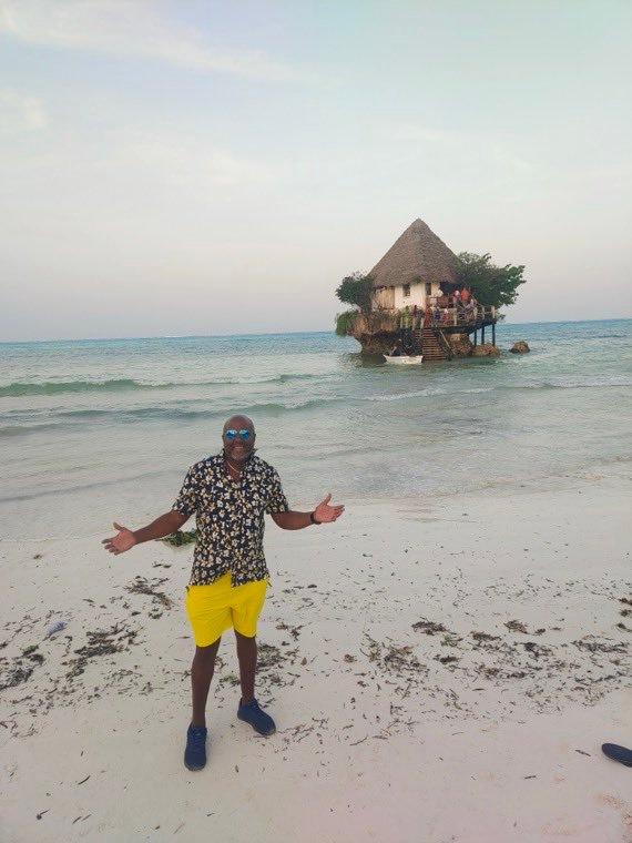 A traveler on the sand facing The Rock restaurant offshore in Zanzibar.