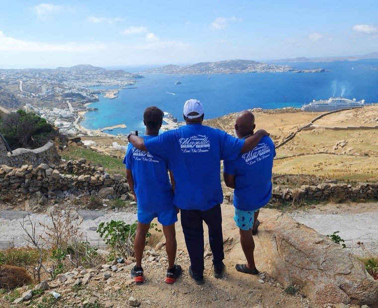 MDV travelers overlooking a blue Mediterranean bay in Greece.
