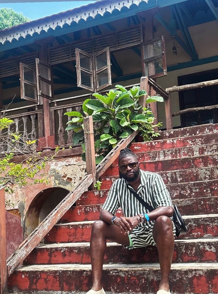 Nick seated on the weathered steps of a historic Stone Town building
