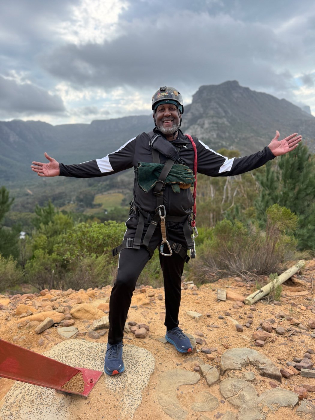 Norman in zipline gear against a mountain landscape